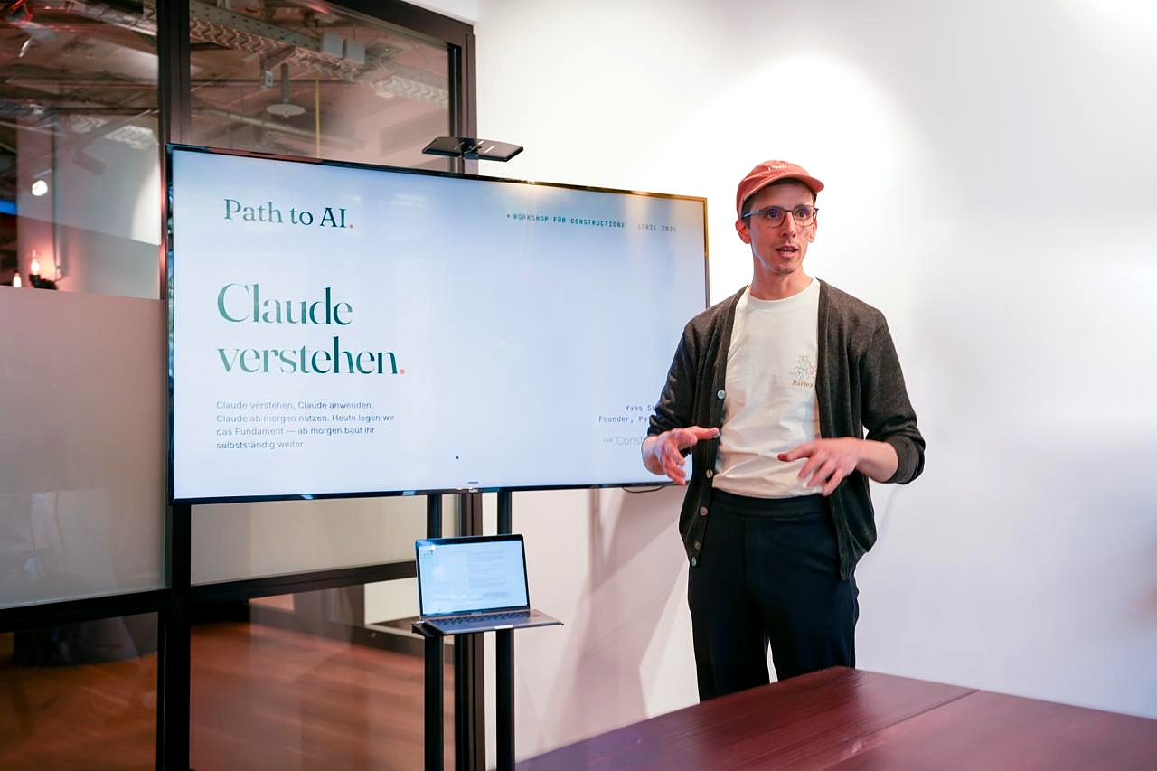 Yves Schleich erklärt Claude vor einem Bildschirm bei ConstructionX.